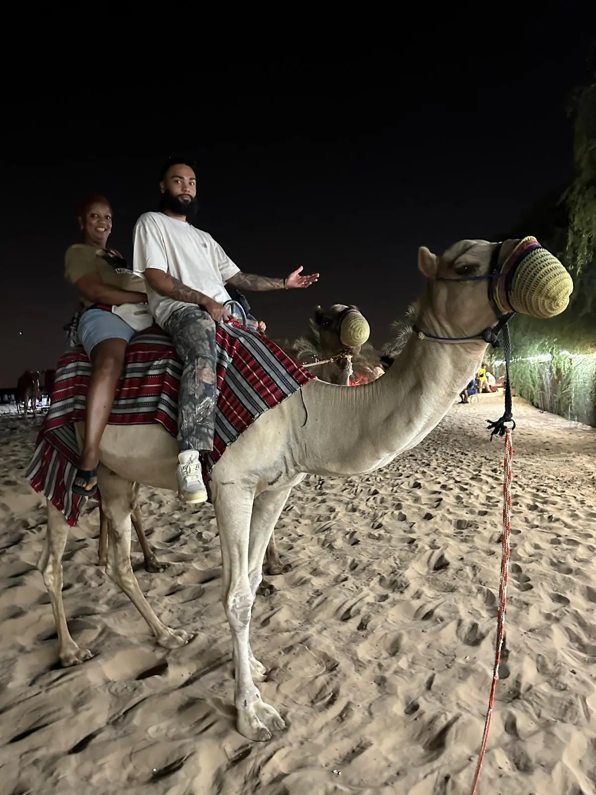 Two travelers riding a camel in the desert at night