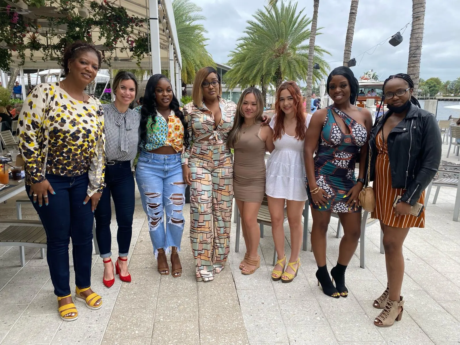 A group of women posing together at an outdoor waterfront restaurant
